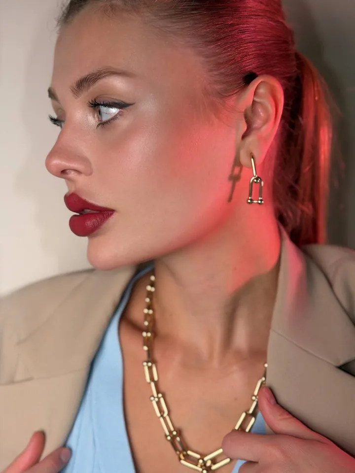 Close-up of a gold link earring and chain necklace